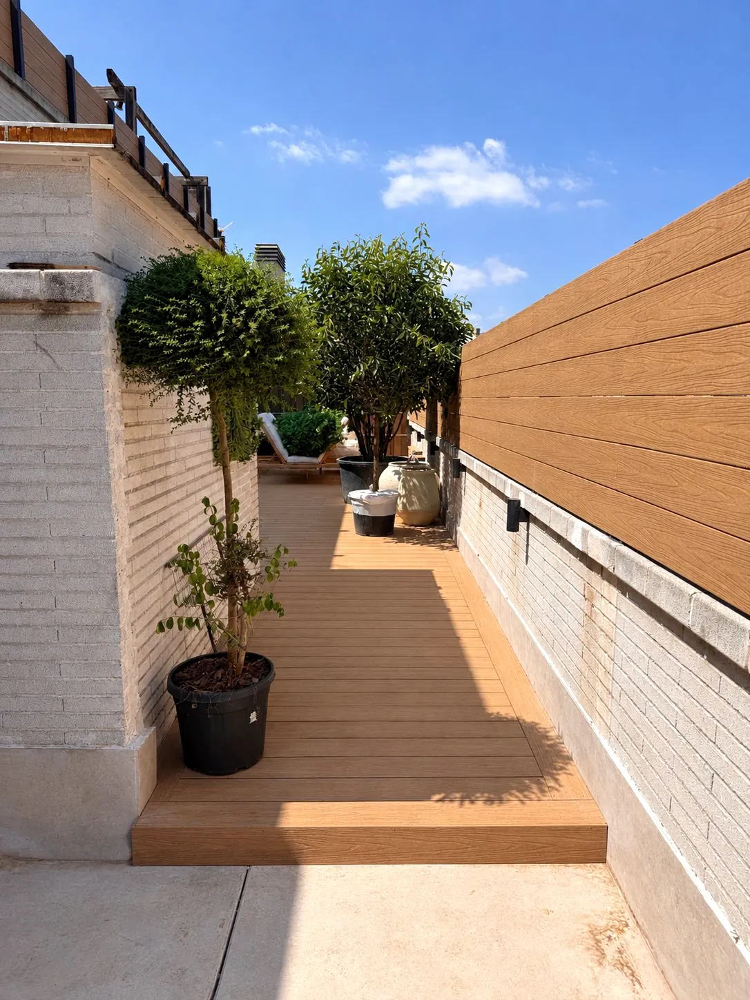 Pasillo de azotea con tarima y jardineras en Blanes